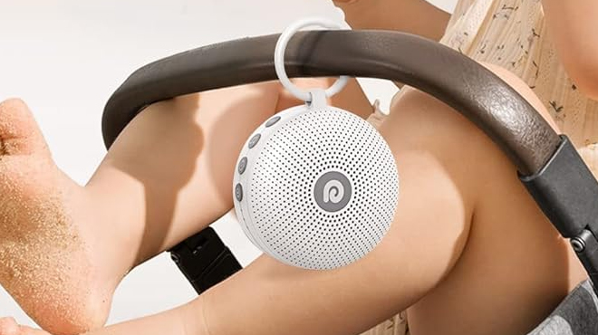 Dreamegg White Noise Machine hanging from a handle of a baby stroller