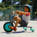 A Child Driving the Razor RipRider 360 Mini Teal 360 Degrees Caster Tricycle