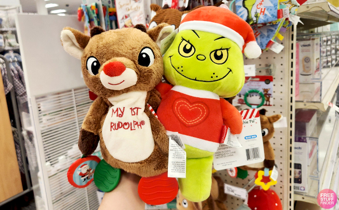 A Hand holding Infantino Grinch Plush and Rudolph the Red Nosed Reindeer 10 Inch Crib Activity Toy