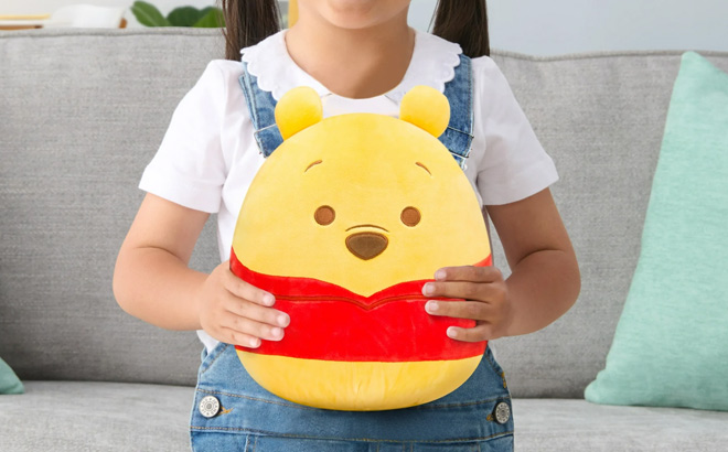 A Kid Holding Squishmallows Disney Winnie the Pooh Toy