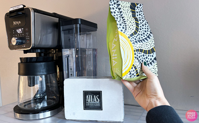 A Person Holding a Coffee Bag next to a Coffee Machine