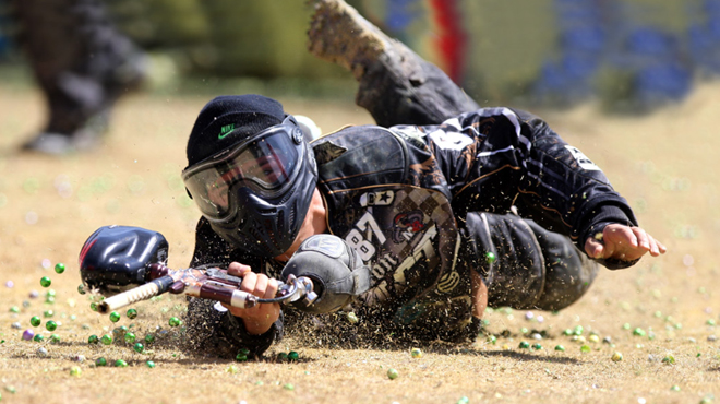 A Person ducking for cover during a paintball game