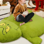 A Person sitting on a Grinch Pillow