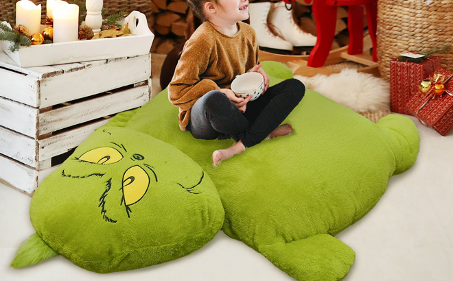 A Person sitting on a Grinch Pillow