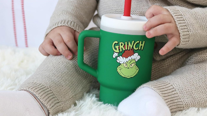 A Toddler Holding the Infantino Green Grinch Limited Edition My 1st Tumbler