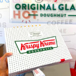 A Woman Holding a Box of Krispy Kreme Dozen Doughnuts