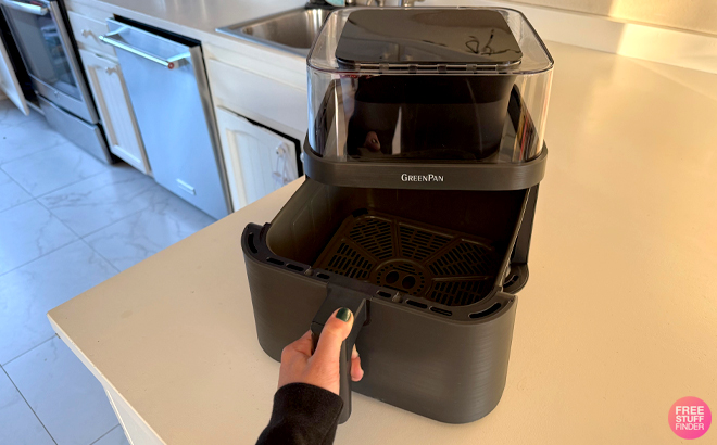 A Woman Opening the Basket on the GreenPan 7 Quart Ceramic Nonstick 360 Clear View Air Fryer