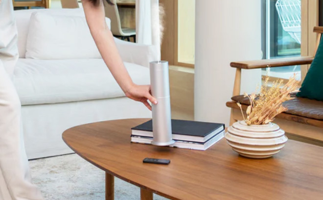 A Woman Putting an Aroma360 Mini Pro Scent Diffuser on a Living Room Table