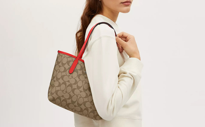 A Woman Wearing Coach Outlet Small City Tote In Signature Canvas