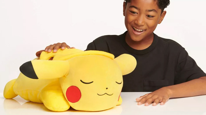 A boy playing with Pokemon Pikachu Sleeping Kids Plush Buddy