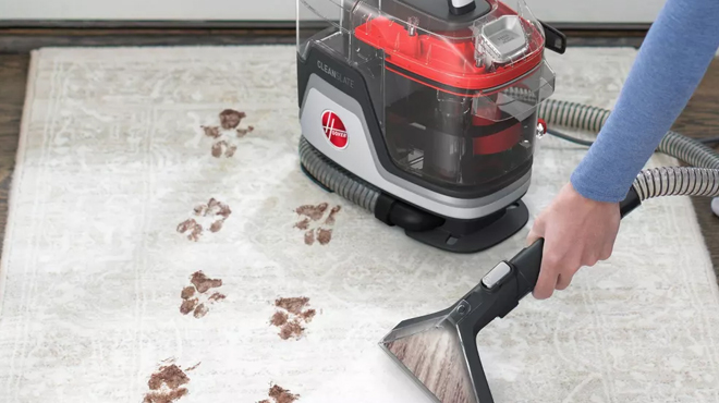 A person cleaning a carpet using a Hoover Cleanslate Portable Carpet and Upholstery Cleaner