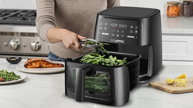 A person cooking vegetables in the Gourmia 8 Quart Digital Window Air Fryer