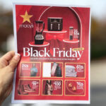 A person holding a Macys Black Friday Pamphlet