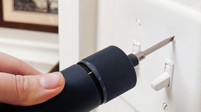 A person using a Hoto Electric Screwdriver to unscrew a power outlet