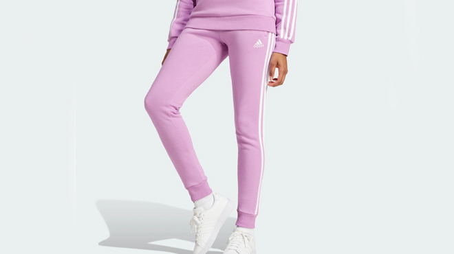 A person wearing a Adidas Womens 3 Stripes Fleece Pants