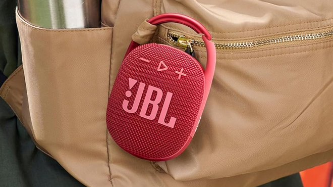 A red JBL Clip 4 Bluetooth Speaker attached to a back pack