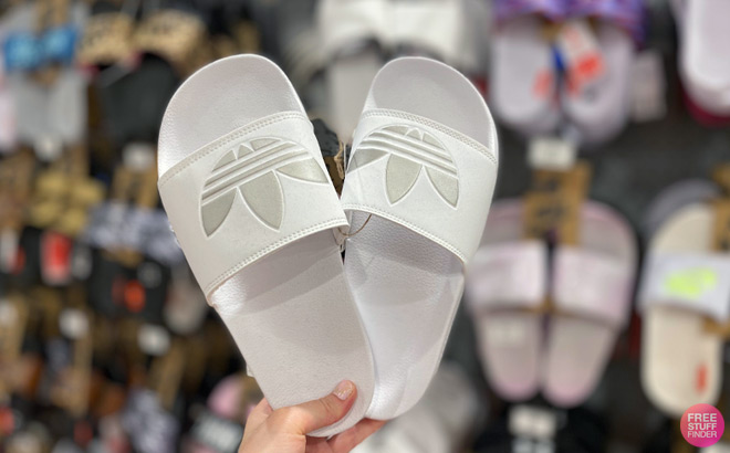 Hand Holding a Pair of Adidas Slides