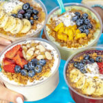 Hands holding Tropical Smoothie Cafe Tropic Bowls