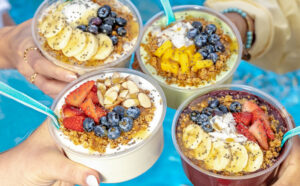 Hands holding Tropical Smoothie Cafe Tropic Bowls