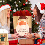 Two People holding a Christmas Gift Bag