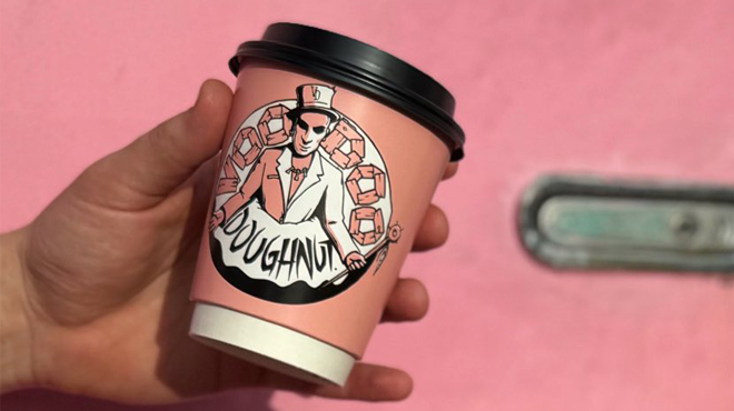 A Hand holding a Voodoo Doughnuts Cup