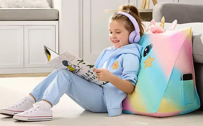 A Little Girl Sitting on the Floor Reading and Using Wedge Pillow for Back Support