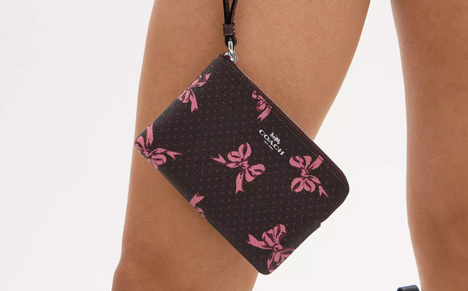 A Person Holding Coach Outlet Corner Zip Wristlet With Bow Print