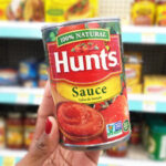 A Person Holding a Can of Hunts Tomato Sauce