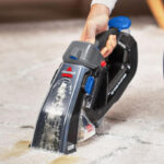 A Woman Cleaning Carpet Stains with the Bissell Pet Stain Eraser Plus Handheld Vacuum