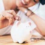 A Woman Depositing a Coin in a Piggybank as Savings