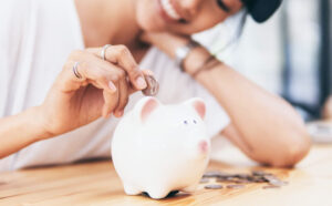 A Woman Depositing a Coin in a Piggybank as Savings