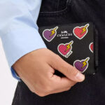 A Woman Holding Coach Outlet Snap Wallet With Heart Bolt Print