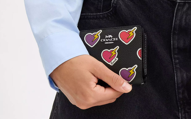 A Woman Holding Coach Outlet Snap Wallet With Heart Bolt Print