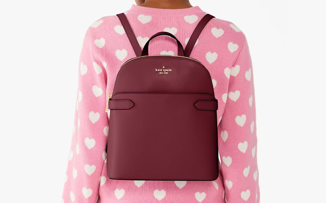 A Woman Wearing Kate Spade Outlet Staci Medium Dome Backpack in Blackberry Preserves