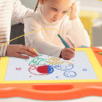 A girl drawing an object with a Bablocvid Magnetic Drawing Board