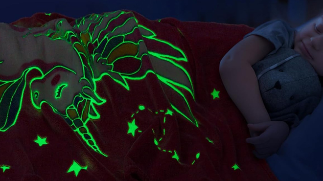 A girls sleeping and covering herself with Levens Glow in the Dark Unicorn Kids Blanket