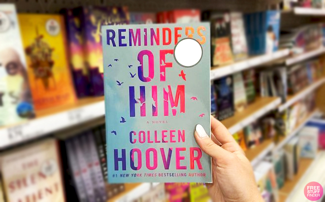 A hand holding Reminders of Him by Colleen Hoover Book