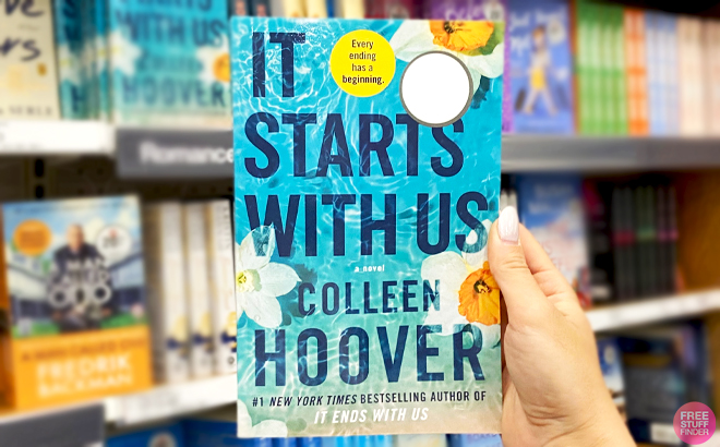 A hand holding a It Starts with Us by Colleen Hoover Book