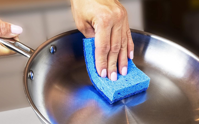 A person cleaning a frying pan using a Amazon Basics Non Scratch Sponge