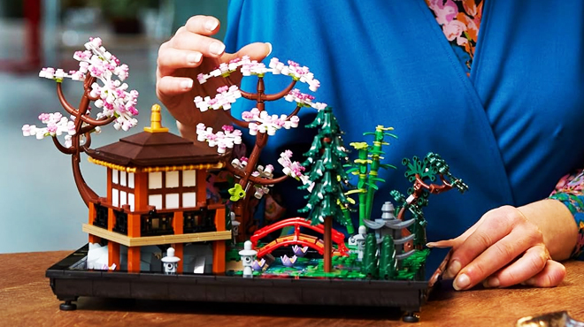 A person fixing a LEGO Icons Tranquil Garden Building Set