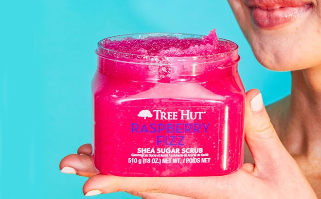 A person holding a Tree Hut Raspberry Fizz Shea Sugar Scrub