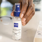 A person holding a bottle of Zeiss Lens Care Spray