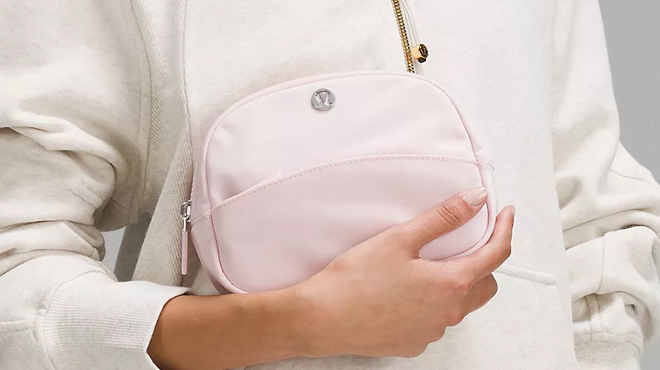 A person holding a pink Lululemon City Essentials Pouch Mini 2L