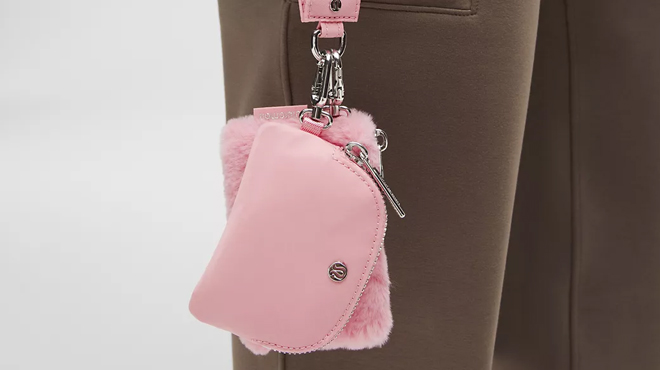 A person holding a pink Lululemon Dual Pouch Wristlet Plush Fleece