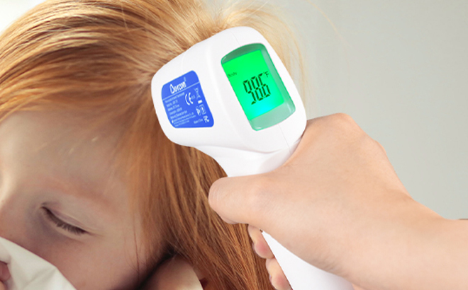 A person measuring the temperature of a child using a Berrcom Non Contact Forehead Thermometer