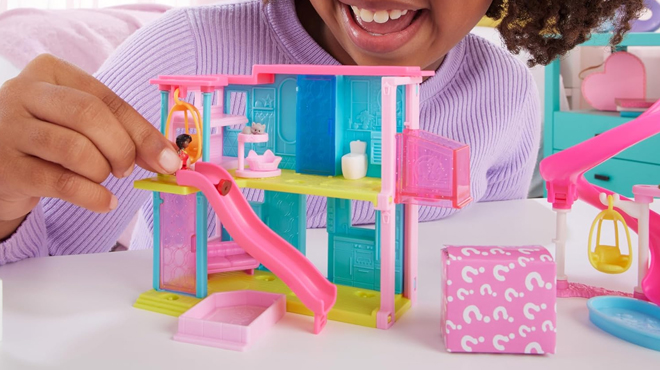 A person playing with Barbie Mini Barbie Land Doll House Set