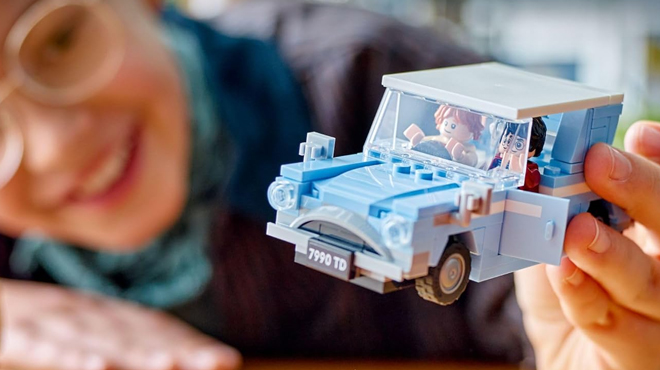 A person playing with LEGO Harry Potter Flying Ford Anglia Car Toy