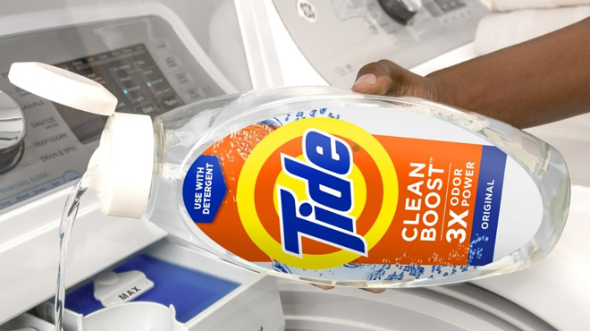 A person pouring Tide Fabric Rinse Original Scent to the washing machine