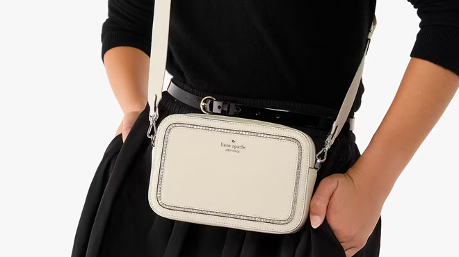 A person slinging a Kate Spade Madison Mini Camera Bag