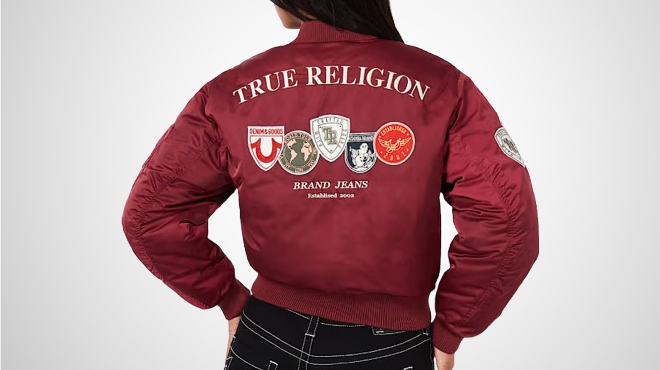 A person wearing a True Religion Patched Bomber Jacket showing the patches at the back